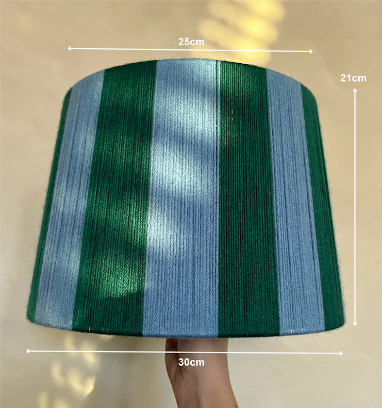 A  Slice Shades handmade yarn drum lampshade, shown with white dimension lines and text indicating measurements of 30cm width, 25cm top width, 21cm height, and a hand holding the bottom edge.
