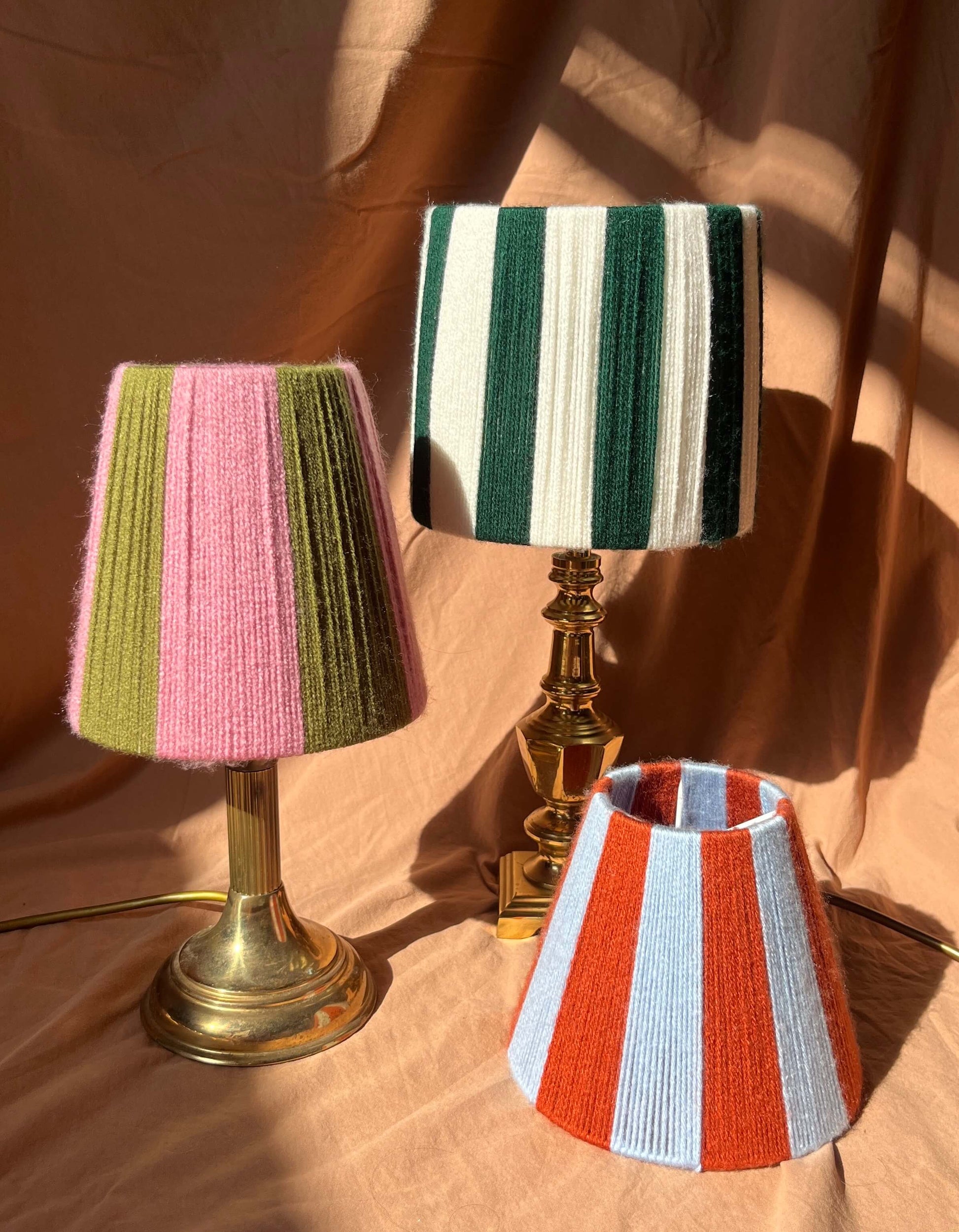 Three Slice Shades Lampshades on bases on a rust background. Hand woven striped string lampshades photographed.