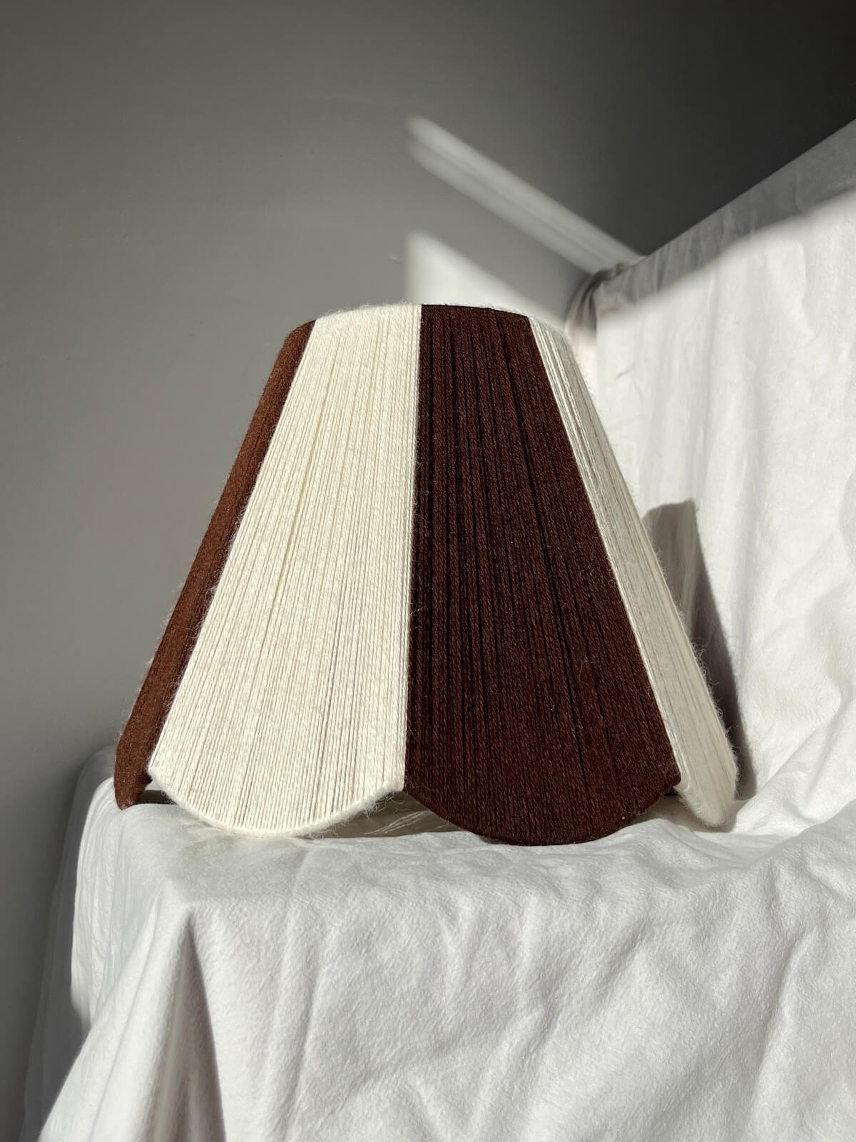 A handmade yarn scallop lampshade by Slice Shades in Ecru and Cocoa white and brown.
