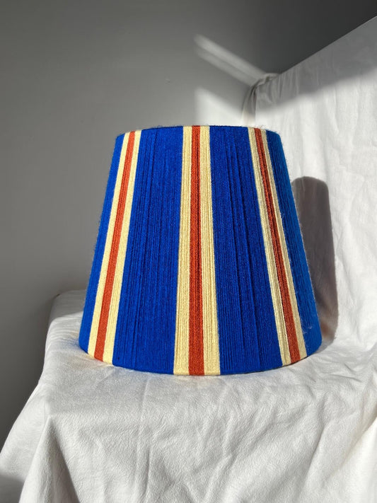 A Slice Shades handwoven striped yarn lampshade in cobalt blue, butter yellow and burnt orange stripes.