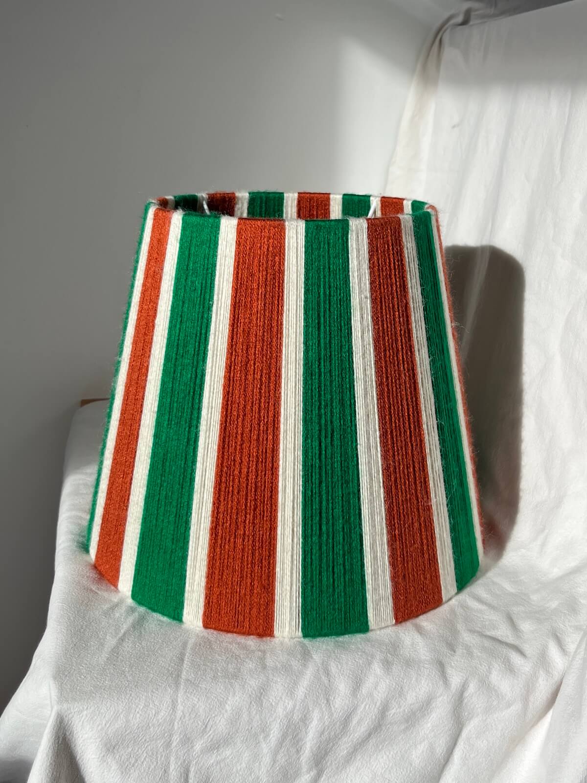A Slice Shades handwoven yarn striped lampshade in Rust, Ecru & Jade Green on a white background.
