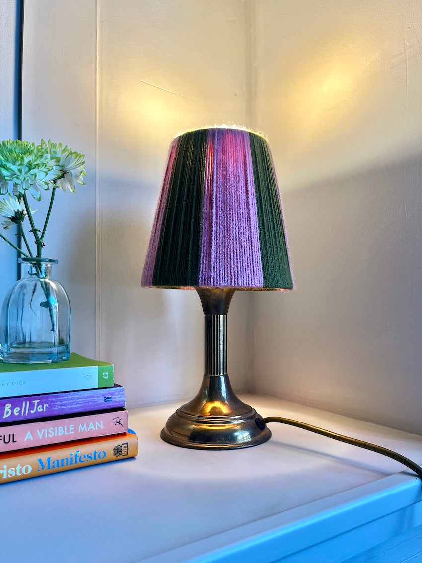A Slice Shades yarn lampshade styled on a brass base on a side table switched on